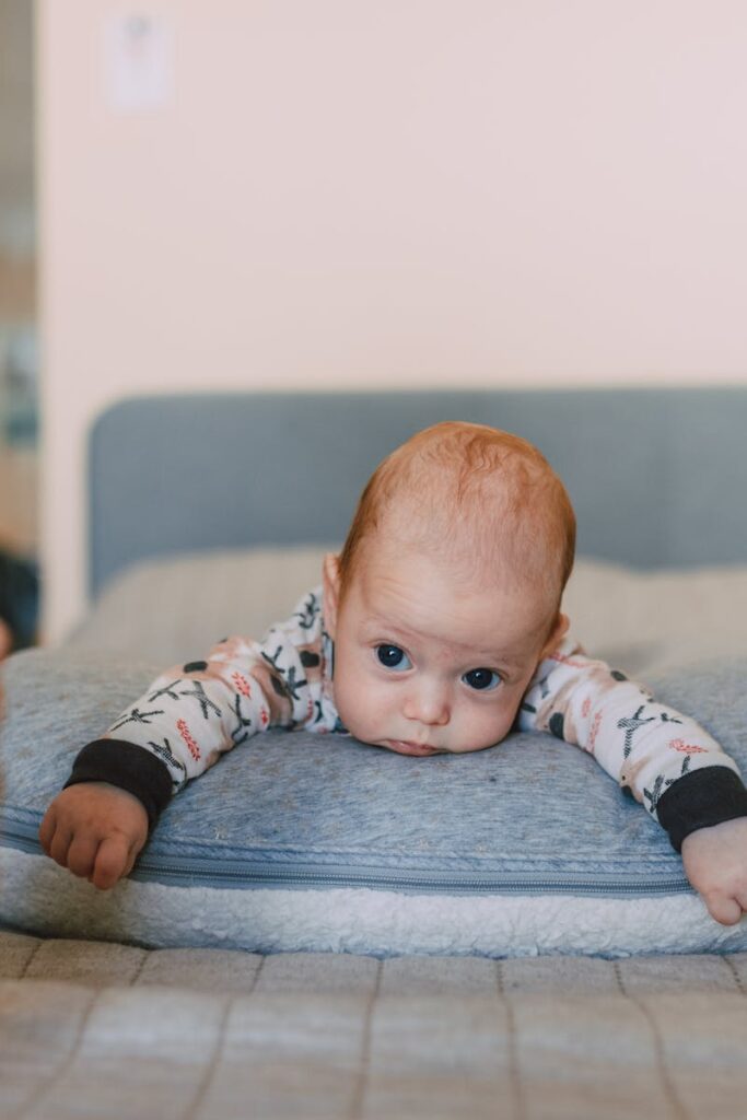 Cute baby on bed gazing at colorful toy, evoking warmth and curiosity.