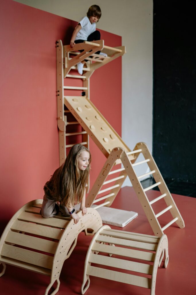 Kids enjoying a wooden climbing frame indoors, fostering fun and activity.