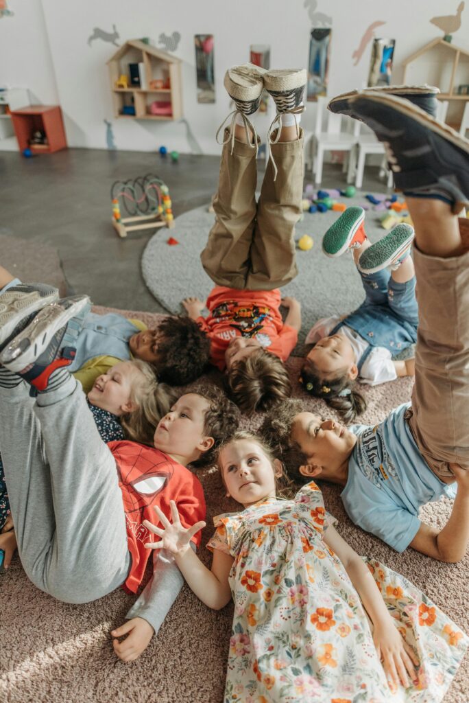 A joyful group of children playing on the floor inside a colorful kindergarten.