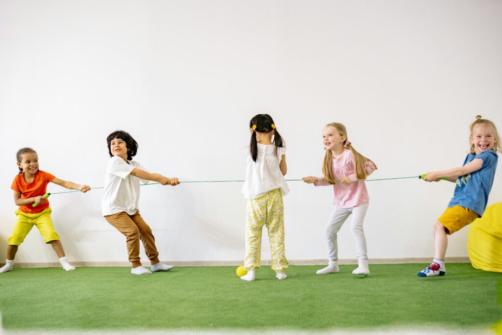 Happy children enjoying a tug of war game indoors, showcasing teamwork and fun.