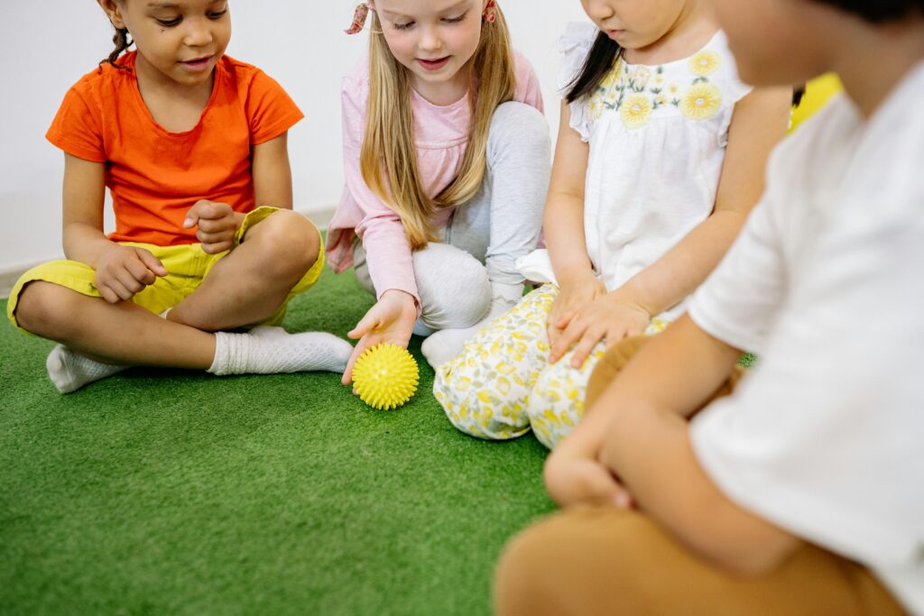 Happy diverse kids enjoying playtime together indoors with a yellow ball.