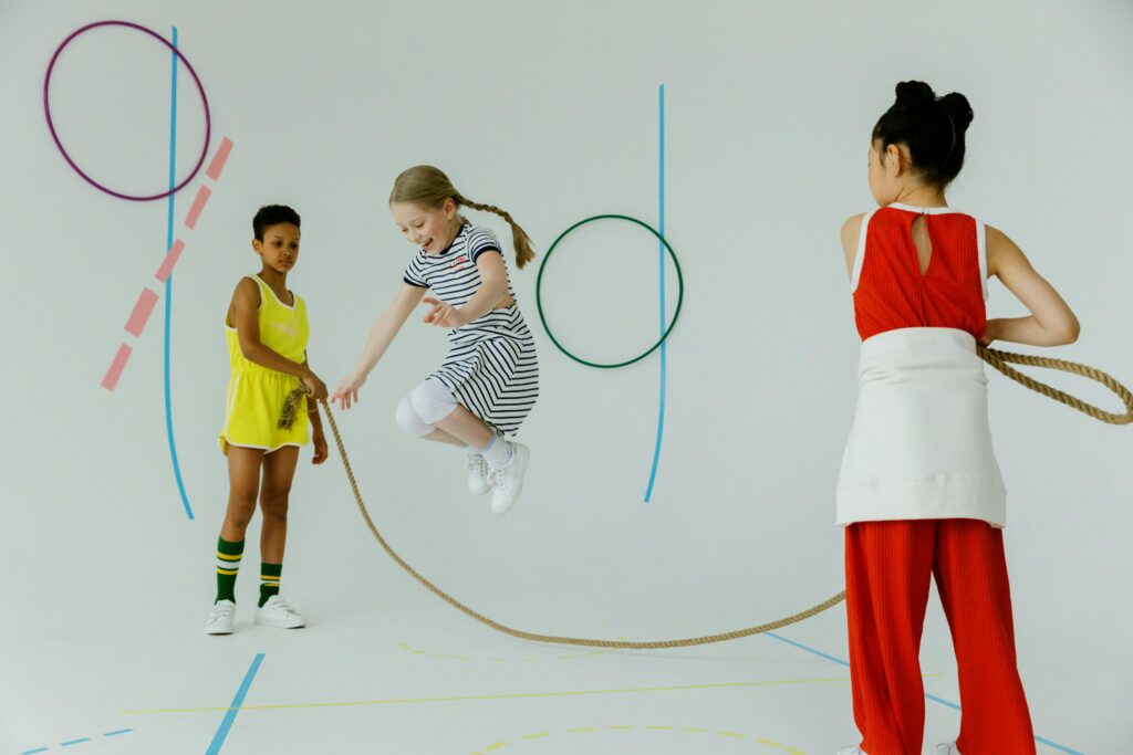 Three children enjoy a fun indoor activity, skipping rope, surrounded by playful decor.