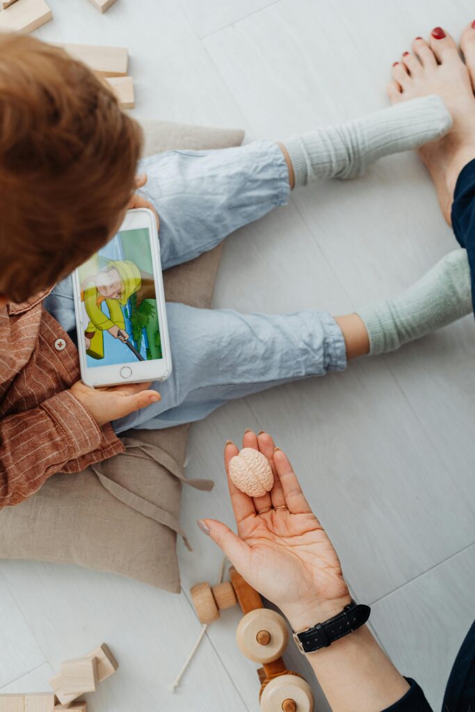 A child watching a video on a smartphone while adults supervise indoors.