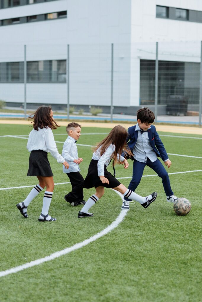 Group of children playing soccer on a school field, enjoying outdoor fun and recreation.