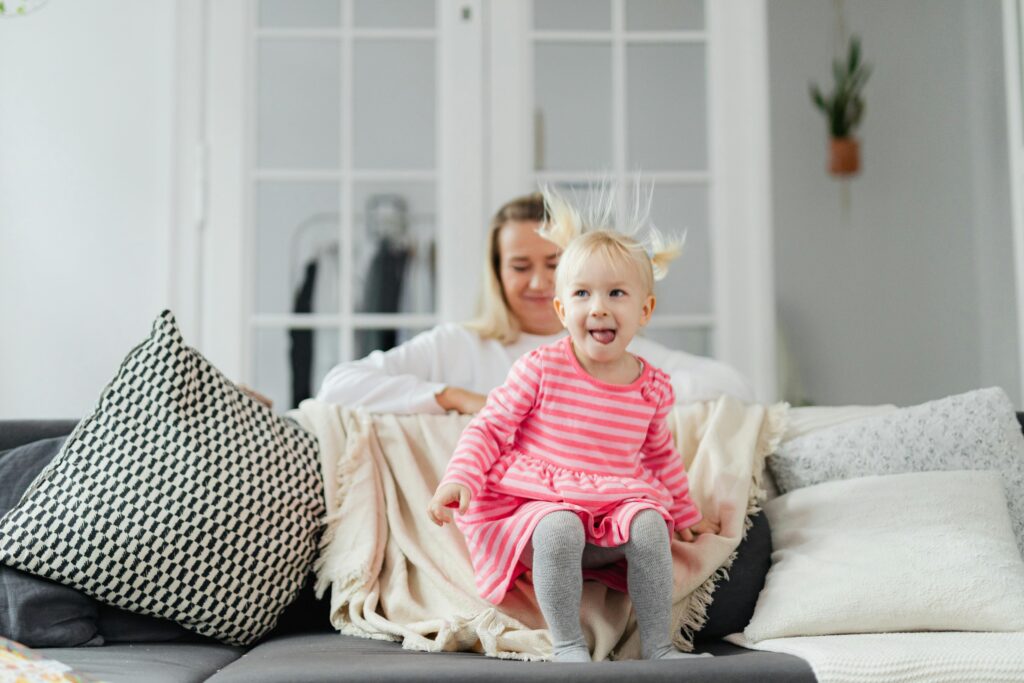 Woman and child playing on a sofa in a living room setting, exuding happiness and joy.
