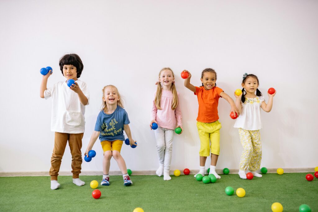 Happy diverse children playing with colorful balls indoors, showcasing fun and friendship.