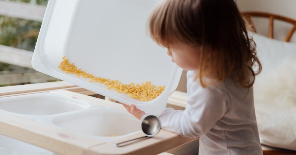 Adorable child playing with pasta in a sensory tray, focusing on fun indoor learning.