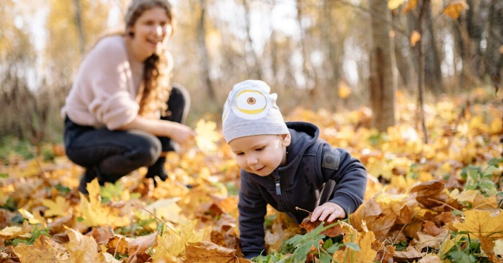 A joyful scene of a mother and baby enjoying the fall leaves outdoors.