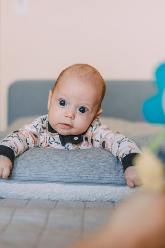 Cute baby on a bed pillow gazing at a colorful toy indoors.