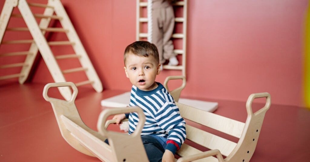 Young boy wearing a striped shirt enjoying a wooden rocker in a colorful indoor playroom.