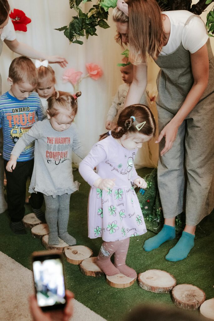 Children engaging in a guided sensory play activity indoors with teacher assistance.