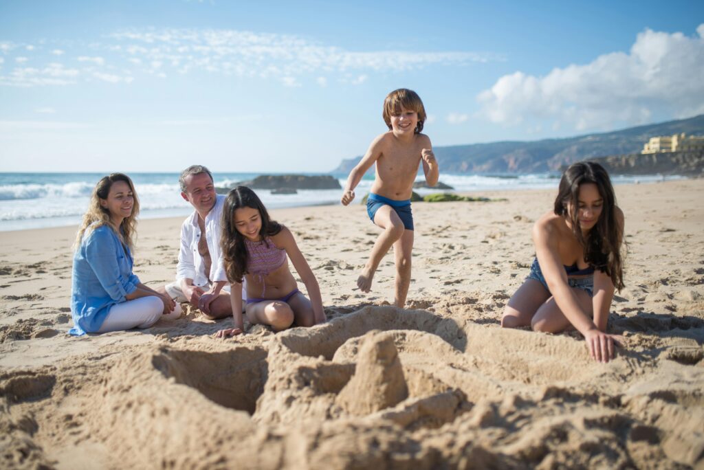 A family enjoys quality time and fun on a sunny beach, building sandcastles together.