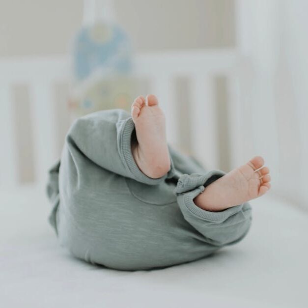 Cute baby feet in pajamas on a soft white crib. Perfect for children's room decor.